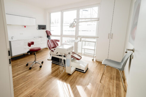 Aufnahme großes Behandlungszimmer mit rotem Zahnarztstuhl ohne Personen