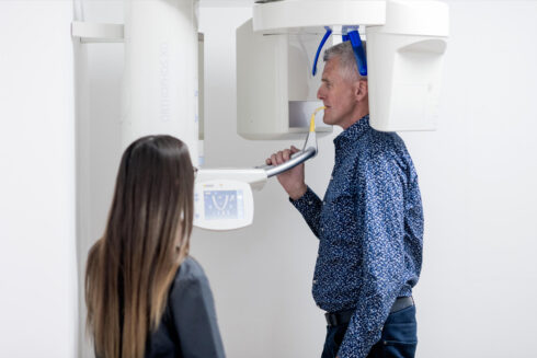 Angestellte röntgt einen älteren Mann mit dem digitalen Röntgengerät