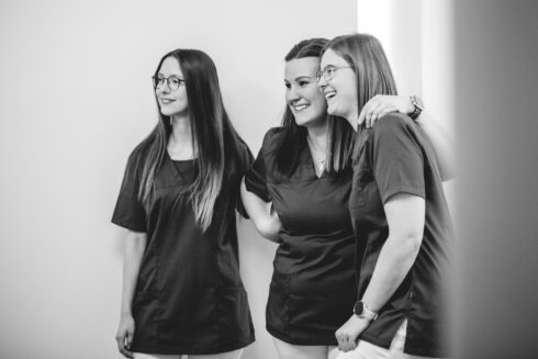 Graustufenbild von 3 weiblichen Angestellten, die nebeneinander stehen und die die Arme übereinander legen